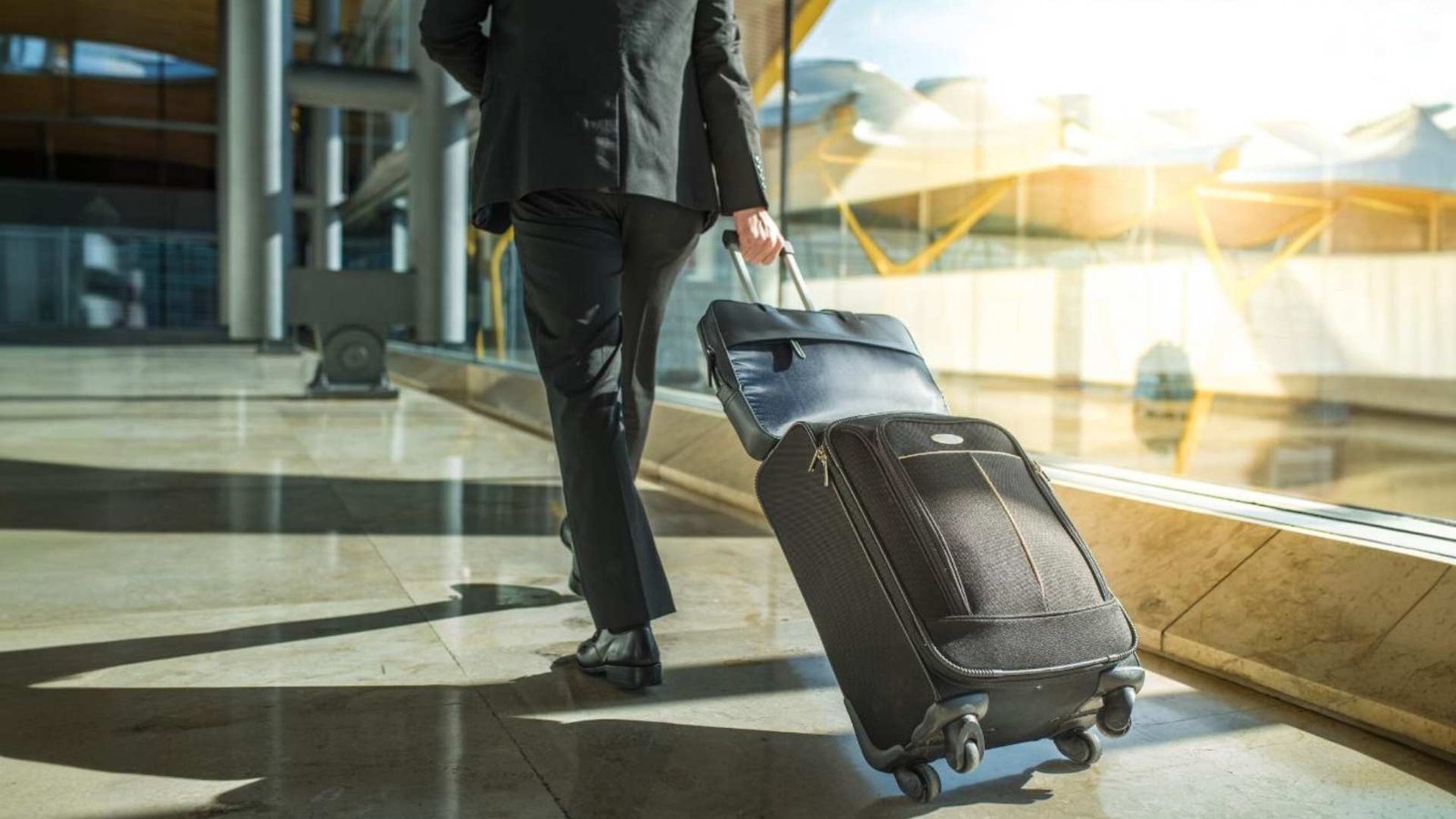 Empresário de volta e pernas andando com bagagem no aeroporto