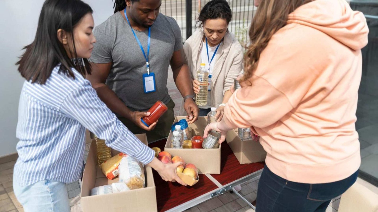 Grupo de diferentes pessoas oferecendo se como voluntário em um banco de alimentos para pessoas pobres