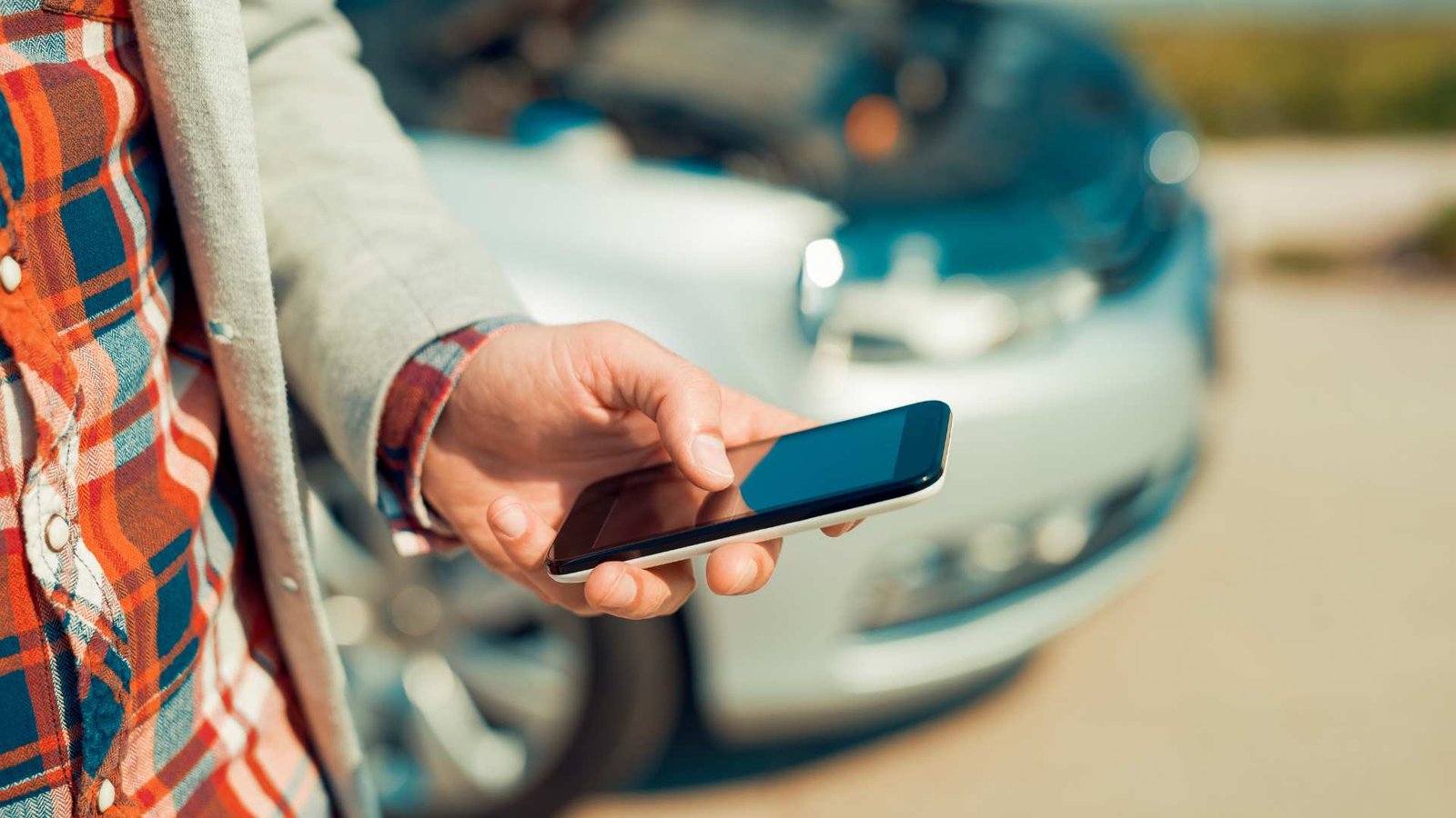 Homem usando smartphone após acidente de trânsito