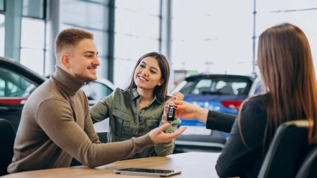 Jovem casal conversando com uma pessoa de vendas em um showroom de carro