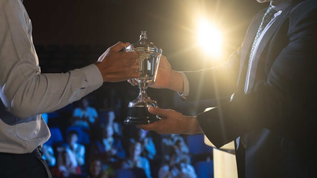 Homem de negócios dando troféu a homem de negócios executivo no palco no auditório